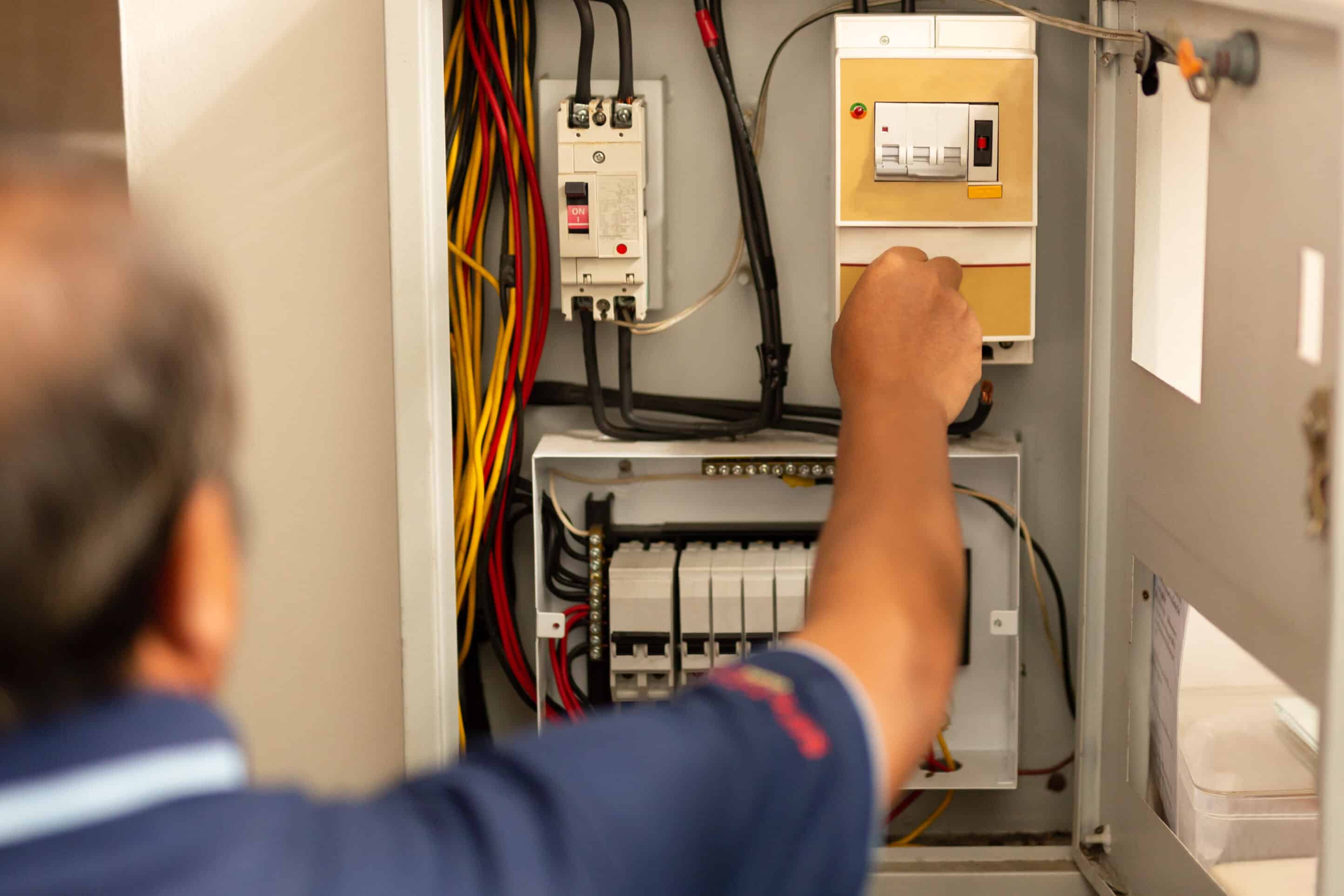 Senior electrician measuring voltage in fuse board. How to turn the power off safely using an electrical panel